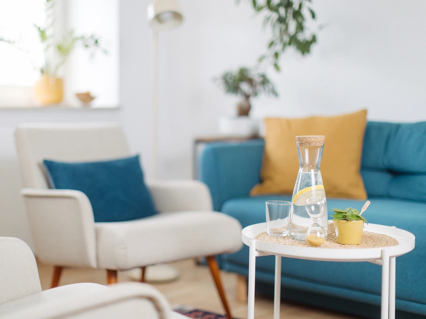 Stillleben des Praxis Raumes mit einem blauen Sofa, zwei beigen Sesseln und einem kleinen Beistelltisch mit einer Wasserkaraffe